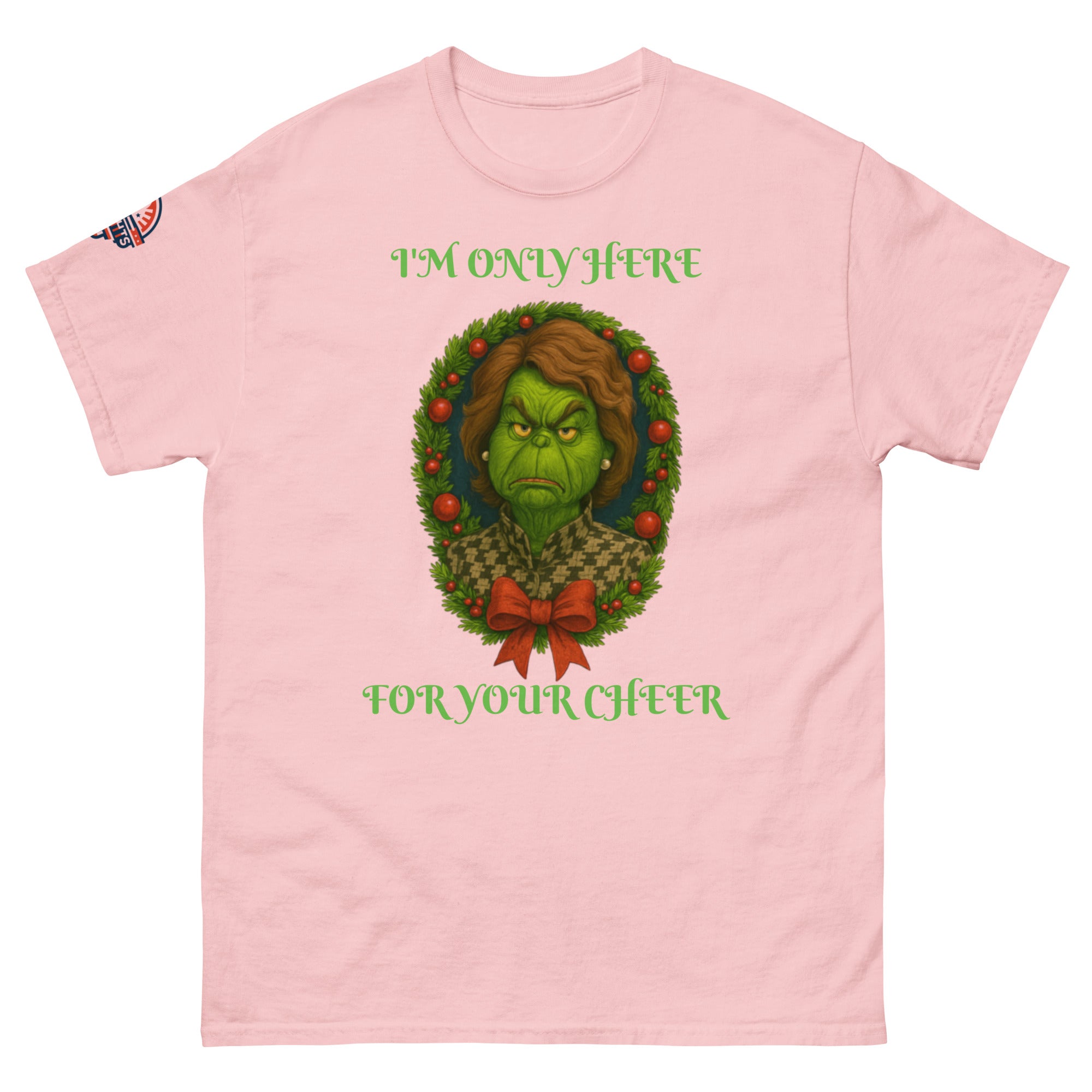Flat lay pink unisex Christmas T-shirt with "I'm Only Here For Your Cheer" political holiday wreath design.